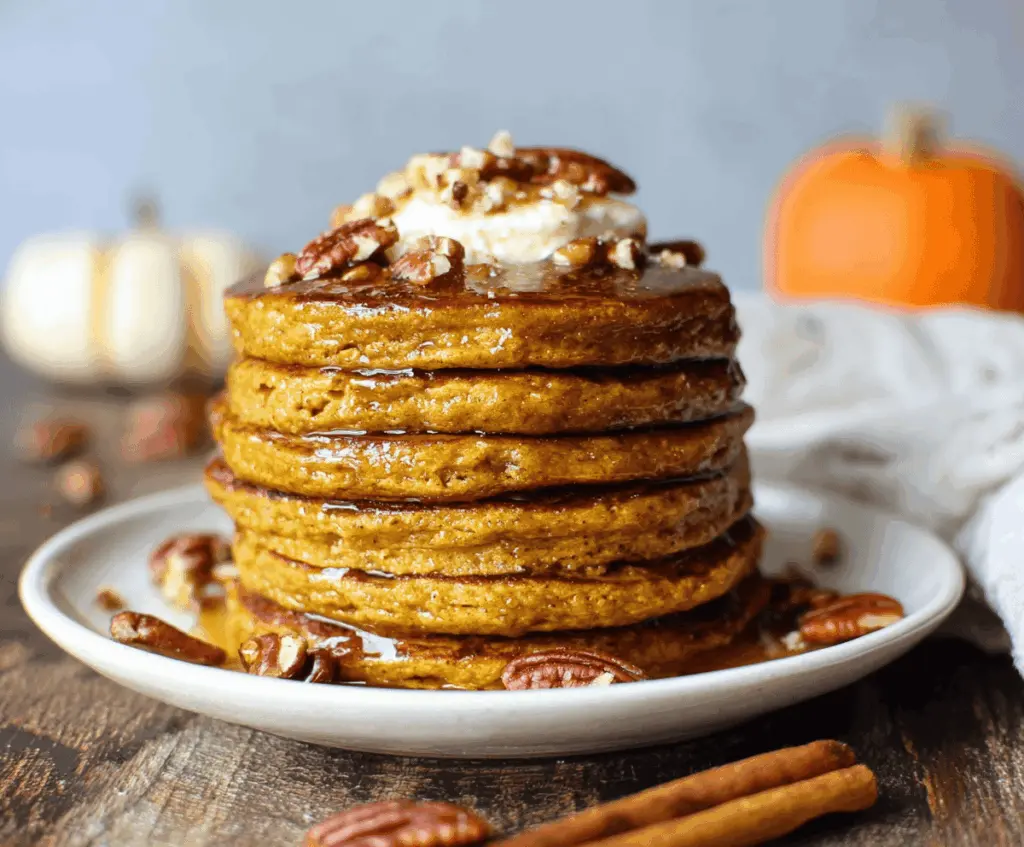 Delicious homemade healthy pumpkin pancakes topped with fresh berries and maple syrup on a breakfast plate