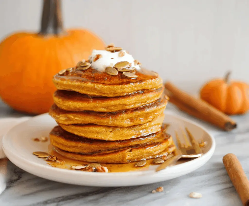 Delicious homemade pumpkin protein pancakes topped with maple syrup and fresh berries, perfect for a healthy breakfast