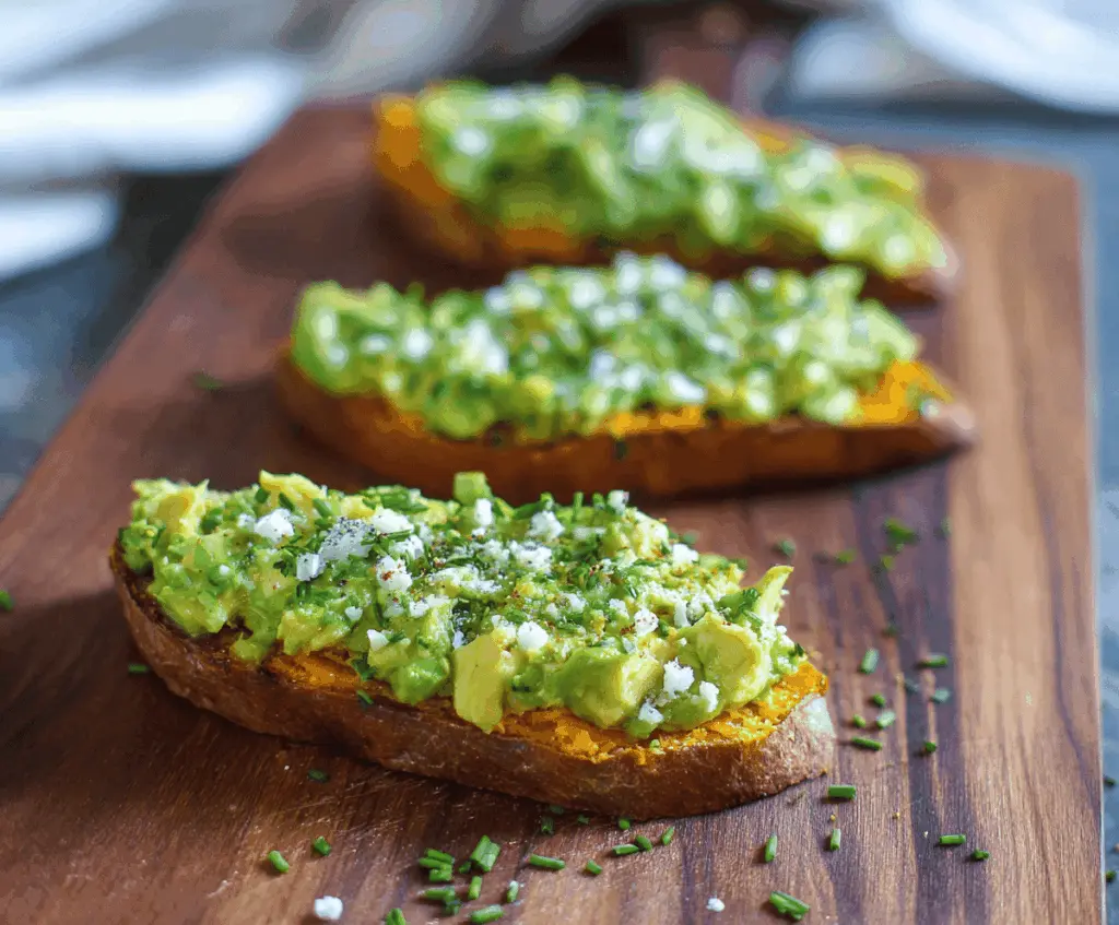Creamy mashed avocado topped with roasted sweet potato slices on whole grain toast, garnished with microgreens for a healthy Sweet Potato Avocado Toast breakfast.