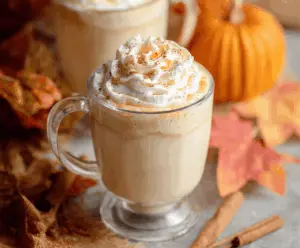 Creamy pumpkin white hot chocolate topped with whipped cream and cinnamon in a cozy mug.