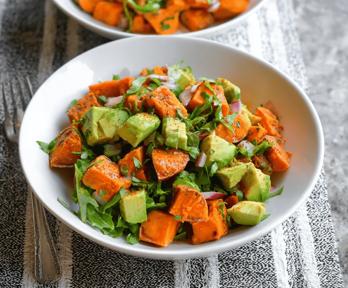 Colorful sweet potato salad with creamy avocado slices and fresh herbs, perfect for a healthy meal.