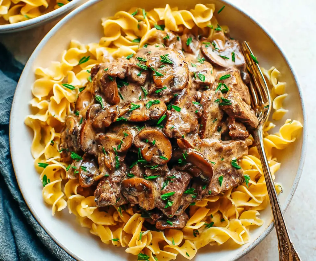 Creamy beef stroganoff served over tender noodles with mushrooms and onions