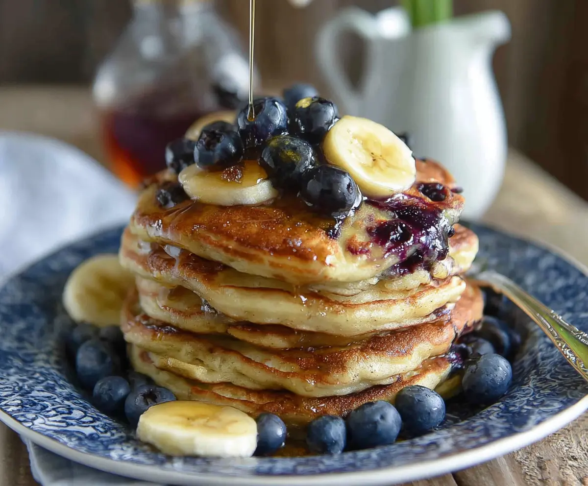 Delicious blueberry banana pancakes topped with fresh blueberries and ripe banana slices on a breakfast plate.