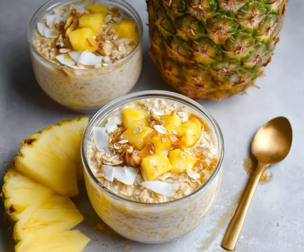 Creamy pineapple overnight oats in a glass jar topped with fresh pineapple chunks for a nutritious breakfast.