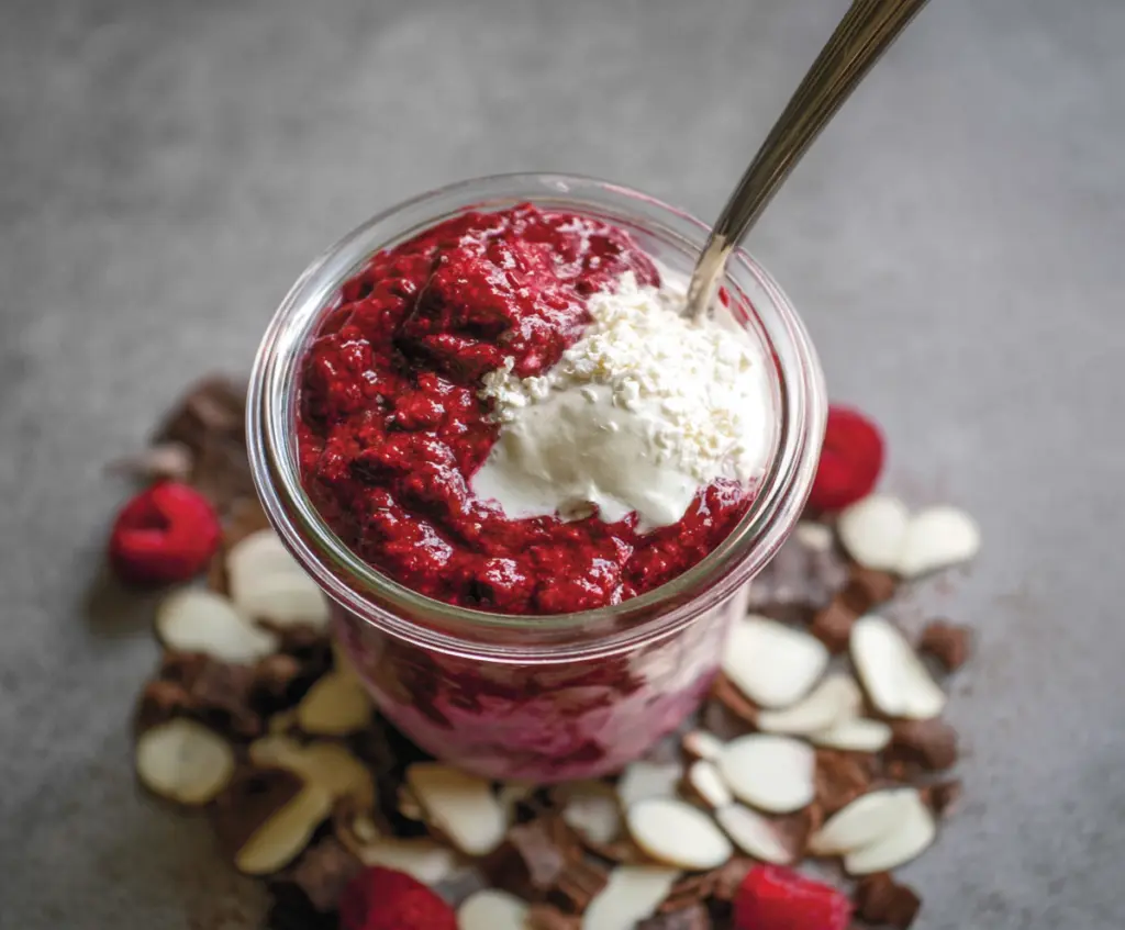Delicious red velvet overnight oats topped with cream cheese and berries, perfect for a healthy breakfast.