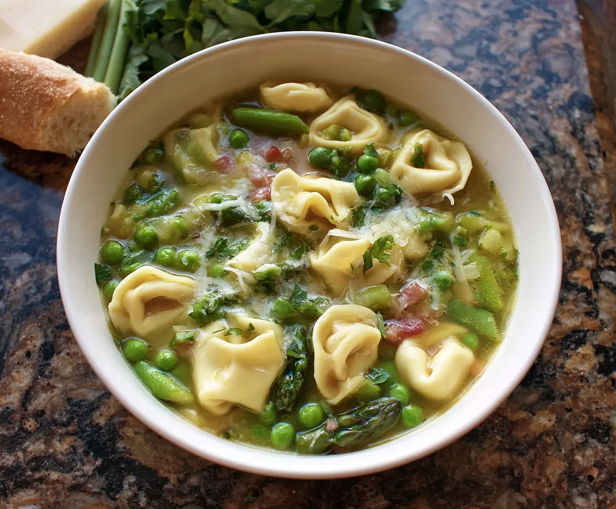 Spring tortellini soup with fresh peas and asparagus in a bowl, perfect for a light, seasonal meal.
