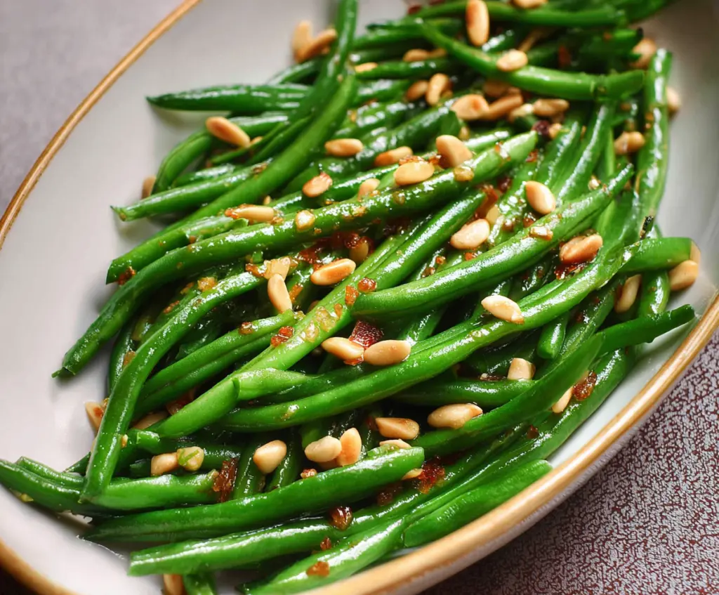 Fresh green beans garnished with toasted pine nuts for a healthy side dish.