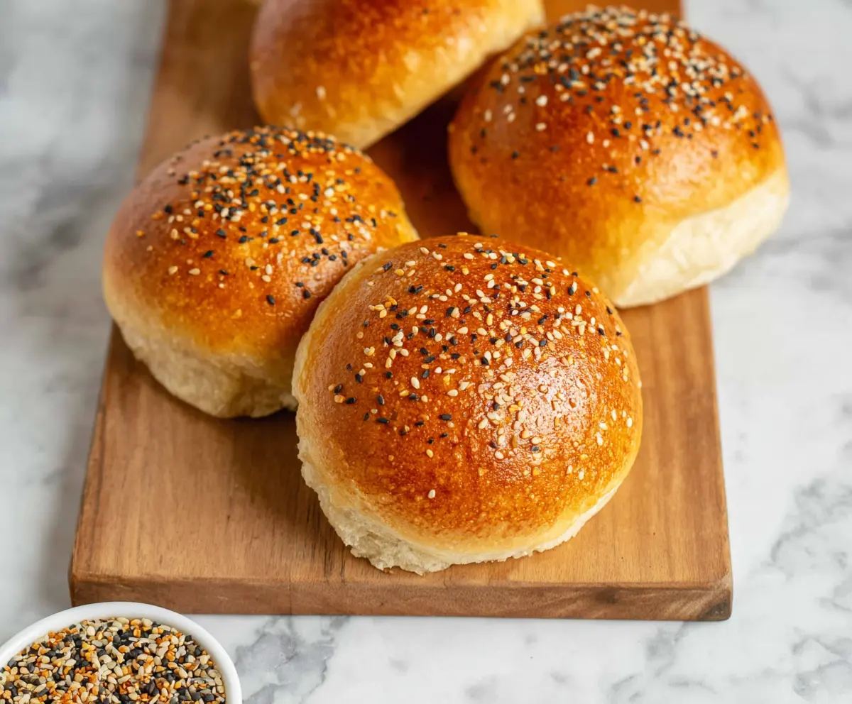 Homemade sourdough discard hamburger buns on a wooden cutting board.